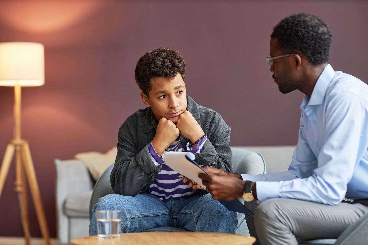 Teenage boy listening to advice of school psychologist