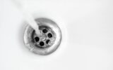 Water in white ceramic sink drains down, close up