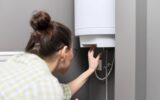 Home water heater, a woman regulates the temperature on an electric water heater, comfort and hot water in the house