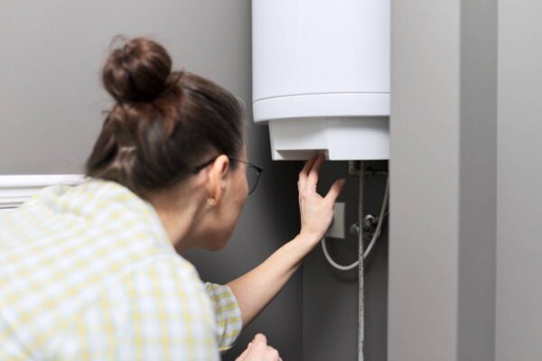Home water heater, a woman regulates the temperature on an electric water heater, comfort and hot water in the house
