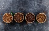 Flat lay of Four different varieties of coffee beans on dark marble background, copyspace
