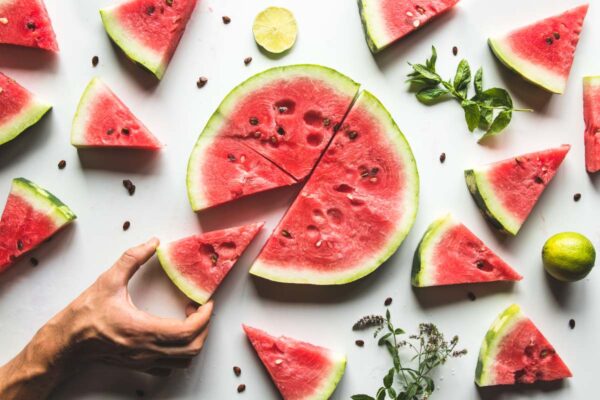 Red slices of ripe watermelon with mint leaves and lime slices on a white background. Top view, flat lay