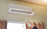 Close up of businessman hand holding remote control directed adjusting of air conditioner. Selective focus