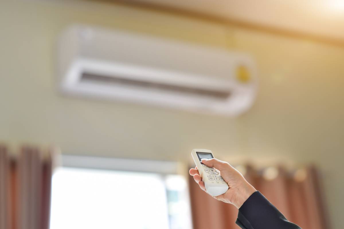 Close up of businessman hand holding remote control directed adjusting of air conditioner. Selective focus